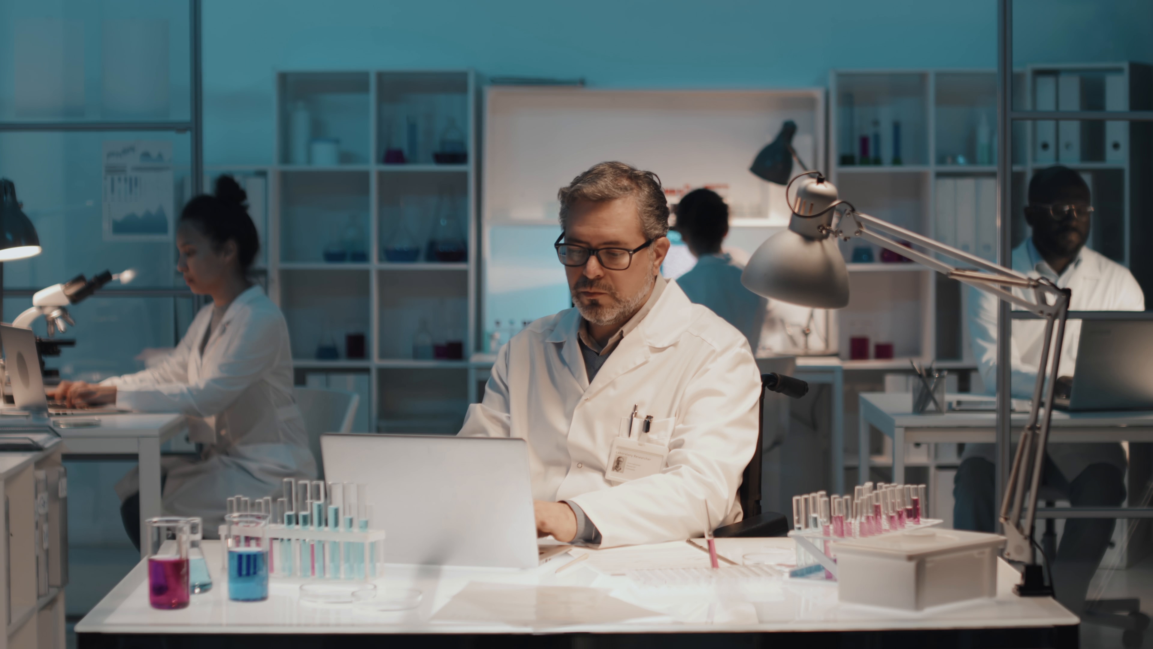 A scientist reviewing results on a laptop at a laboratory bench